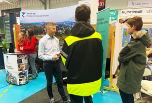 Ein lærar på utdanningsmessa som informerer om skulen sitt tilbod til to ungdomar